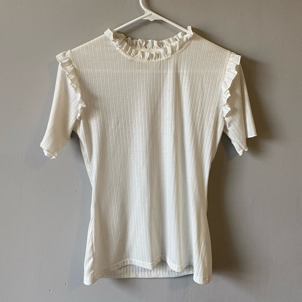 White ribbed t-shirt with ruffles lining the neck and shoulders